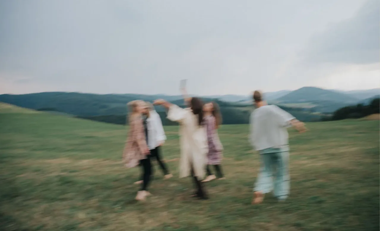 Eine Gruppe tanzt ausgelassen auf einer Wiese vor den Hügeln des Sauerlands