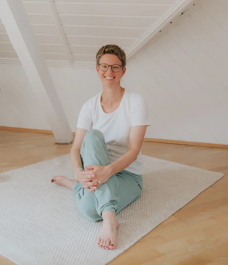 Frau sitzt auf der Yogamatte